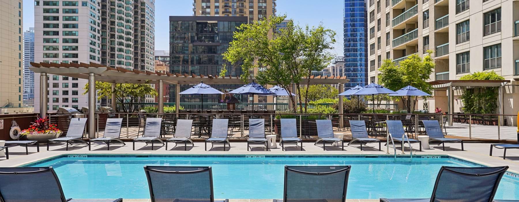 One Superior Place apartments with a pool and lounge chairs with an outdoor grill station. 
